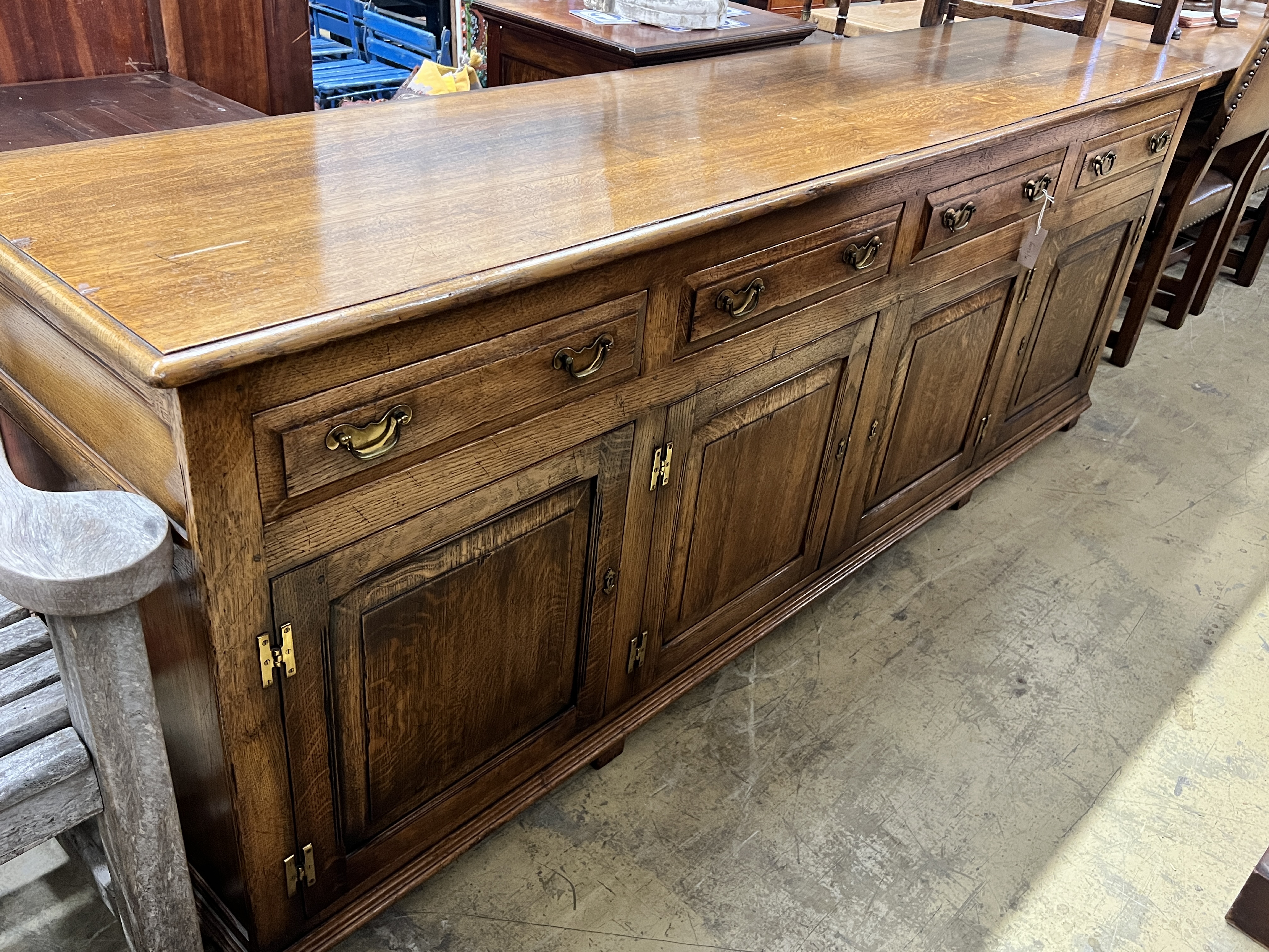 A large reproduction 18th century style oak sideboard, with four drawers and two pairs of hinged panelled cupboards, length 220cm, depth 50cm, height 83cm